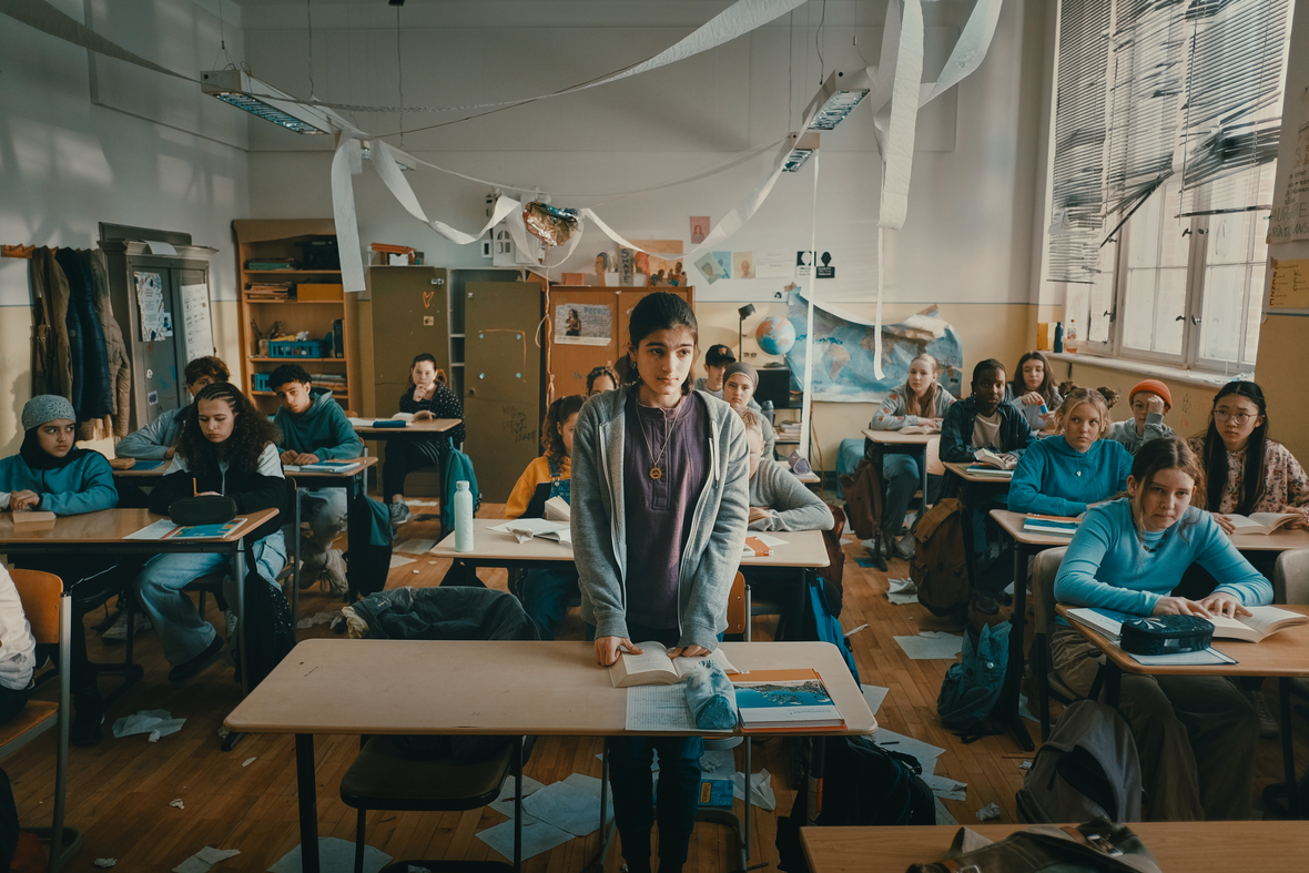 Man sieht die Hauptfigur Mona aus dem Film "Sieger Sein" in ihrer neuen chaotischen Klassen, Papier wird geworfen, die Schüler und Schülerinnen rufen und stören den Unterricht.