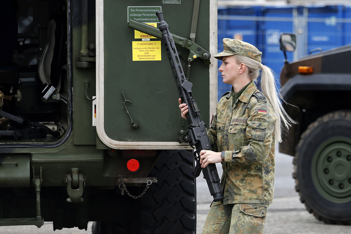 Eine Soldatin trägt ein Maschinengewehr.