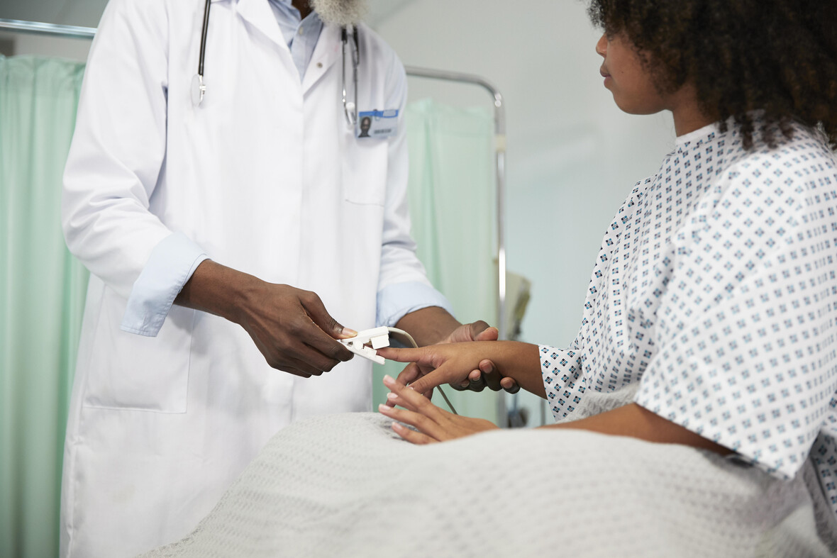 Arzt untersucht den Puls einer Patientin im Krankenhaus mit einem Pulsoximeter. 