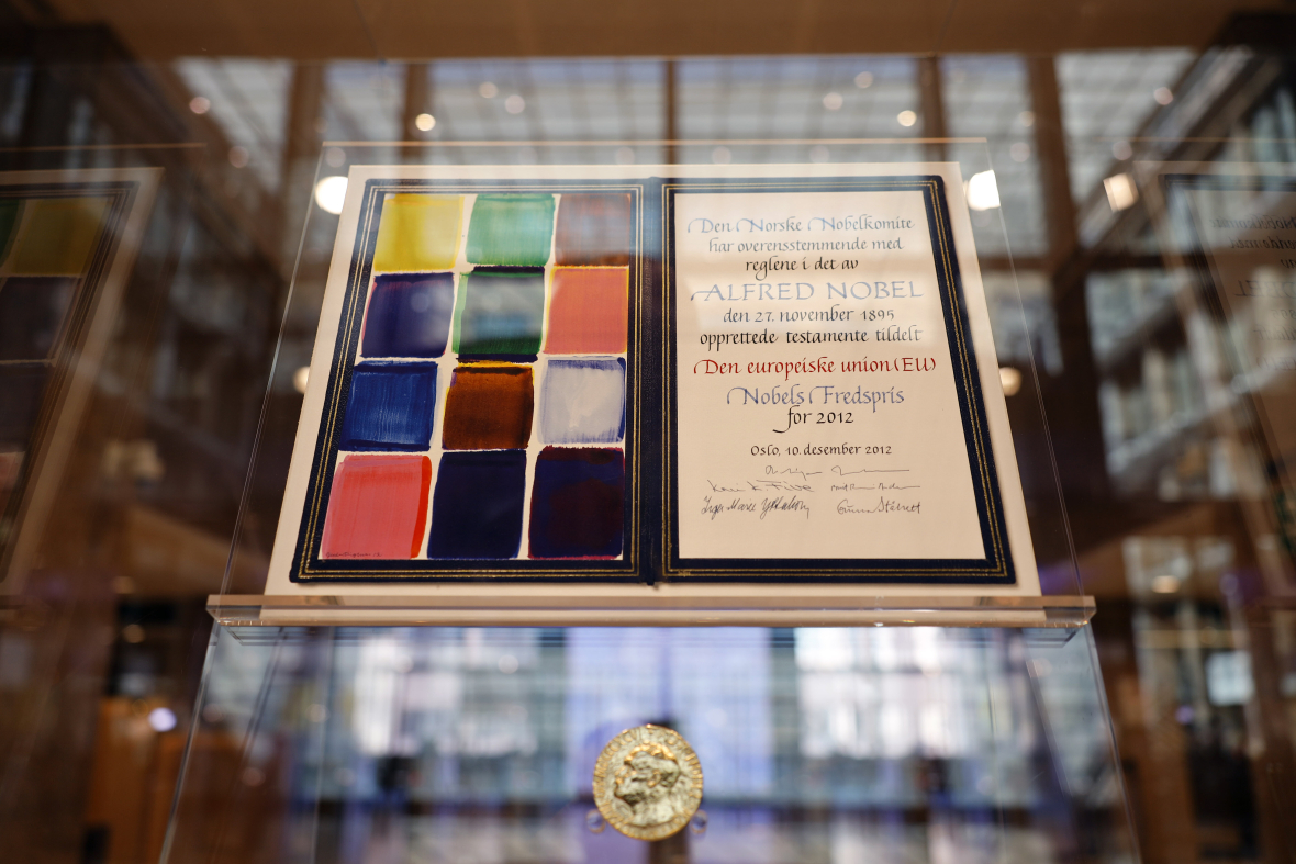 Eine Urkunde und darunter eine goldene Medaille hinter Glas.