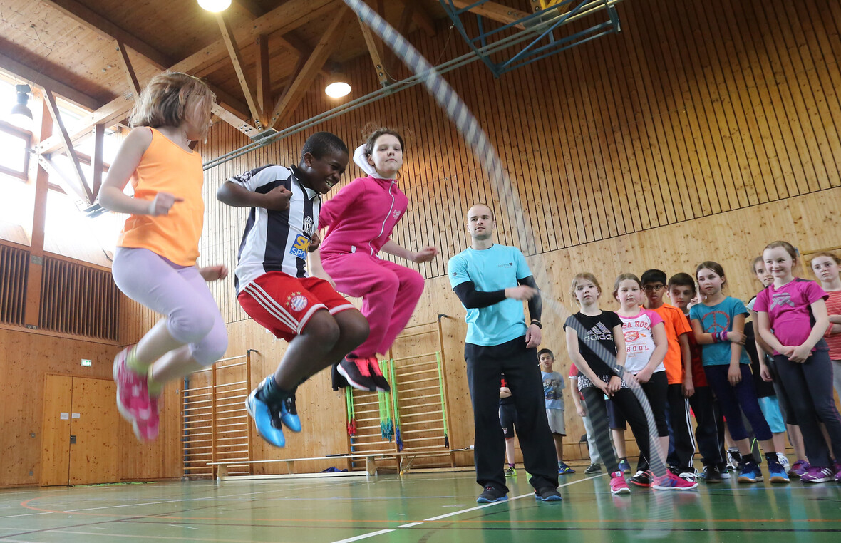 Kinder springen zusammen Seil
