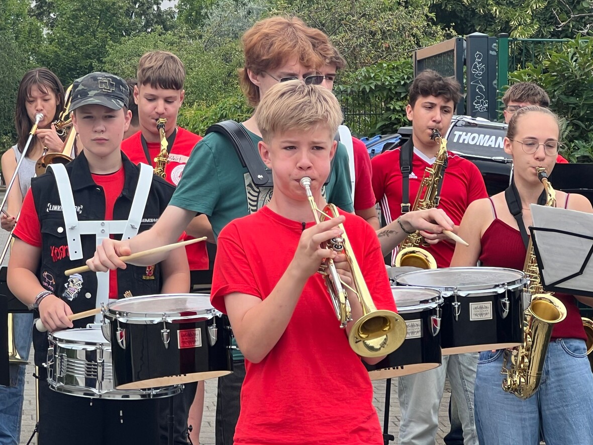 Jonas mit Trompete, ein Orchester-Straßenzug mit verschiedenen Instrumenten im Hintergrund