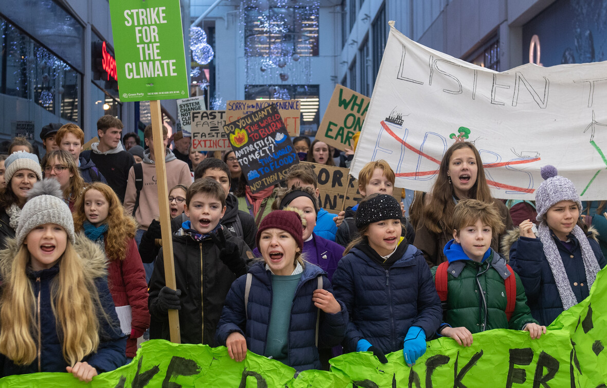 Große Gruppe von Kindern hält Protestschilder hoch.